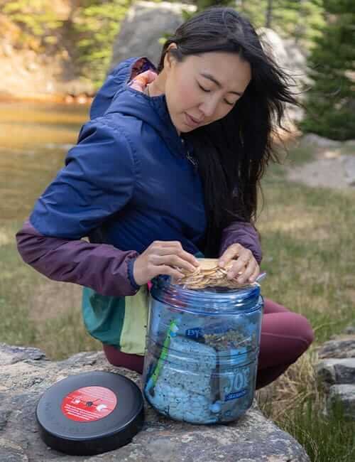 BearVault BV475-Trek canister being packed by a hiker outdoors