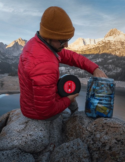 BearVault BV500-Journey canister used by a hiker resting on a rock in the mountains