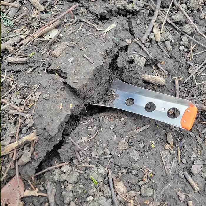 BoglerCo Ultralight Trowel lying on rocky trail soil, showing spine grip holes