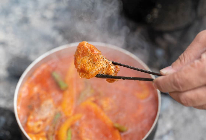Evernew Nicktsucam – tongs lifting food from a pot outdoors