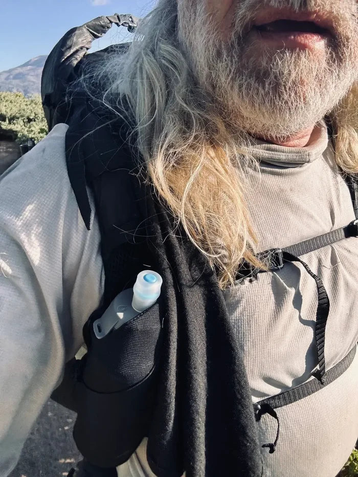 Glacial Gear Trail Rag Elite worn as a neck wrap by a hiker with a backpack outdoors