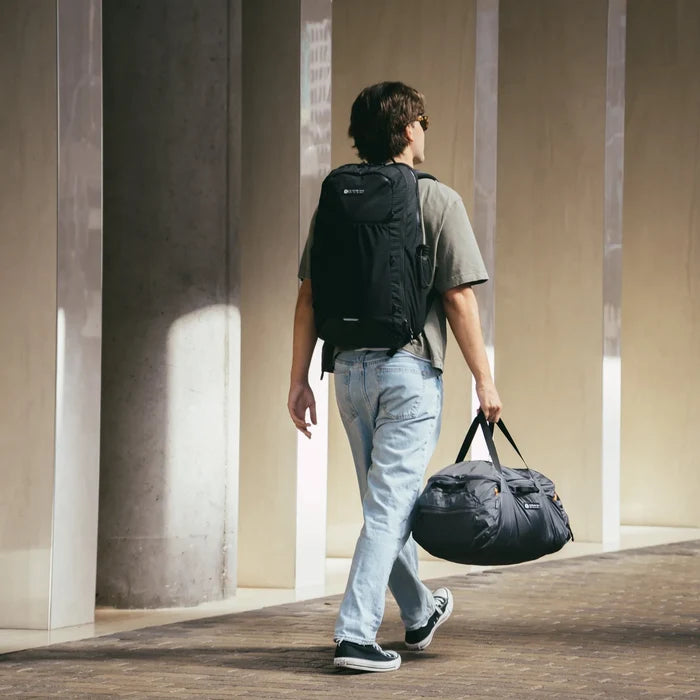 Gossamer Gear Aero Jet V2 worn by a traveler walking with a matching duffel bag