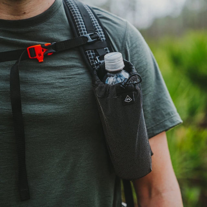 Hyperlite Mountain Gear Bottle Pocket on a shoulder strap holding a water bottle, hiker outdoors