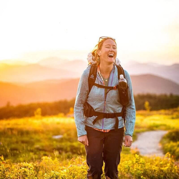 Hyperlite Mountain Gear Bottle Pocket worn by a hiker laughing on a ridge at sunset, bottle stowed