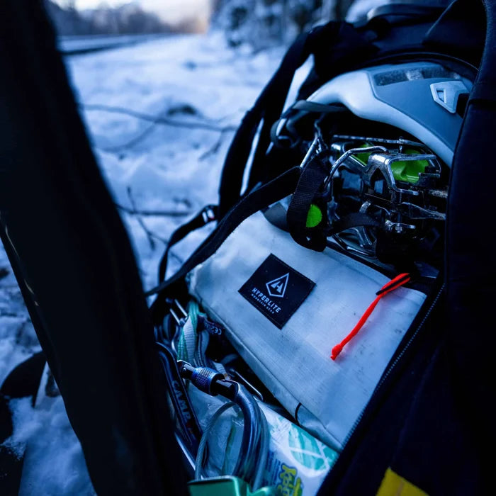 Hyperlite Mountain Gear Prism Ice Screw Case clipped to a harness with crampons and ice tools, night