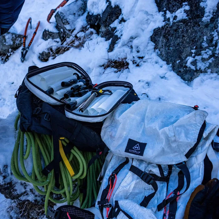 Hyperlite Mountain Gear Prism Ice Screw Case open on a pack, ice tools and rope nearby on a snowy climb