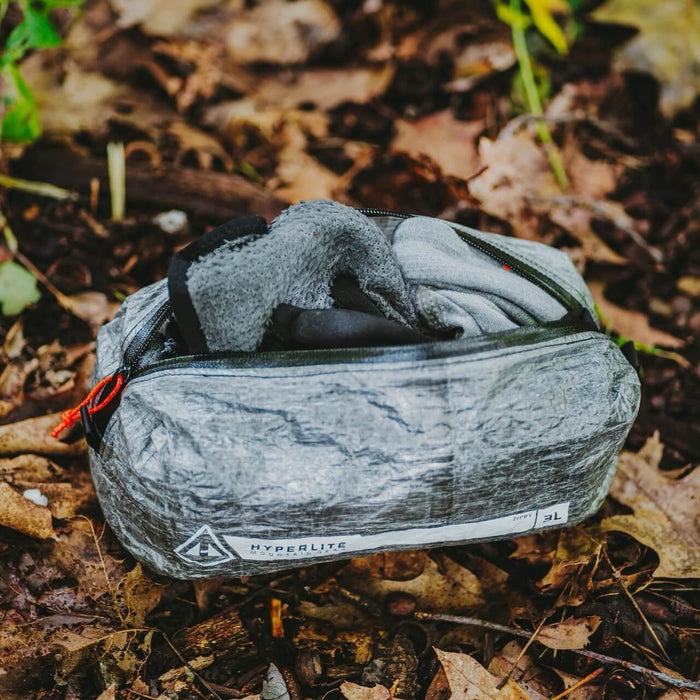 Hyperlite Mountain Gear Zippy 3L pouch open, packed with a fleece jacket, on leaves