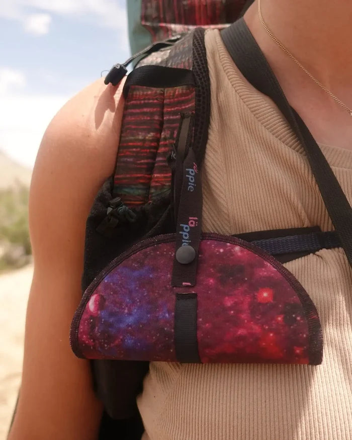 Läppie Pee Cloth in Universe print – clipped to a backpack strap, worn