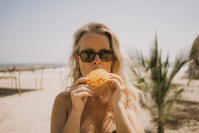 Ombraz Cammina armless sunglasses worn by a woman eating at the beach