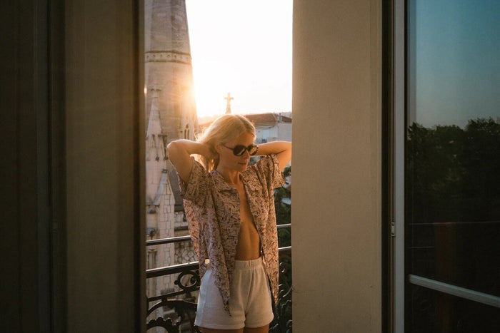 Ombraz Cammina armless sunglasses worn in a sunlit doorway, arms raised