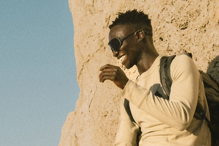 Ombraz Refugio armless sunglasses worn by a man leaning against a rock face