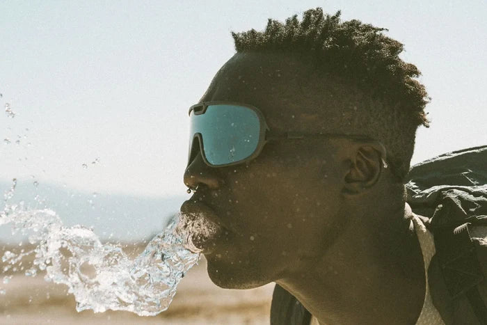 Ombraz Refugio armless sunglasses worn by a man with water splashing at his face