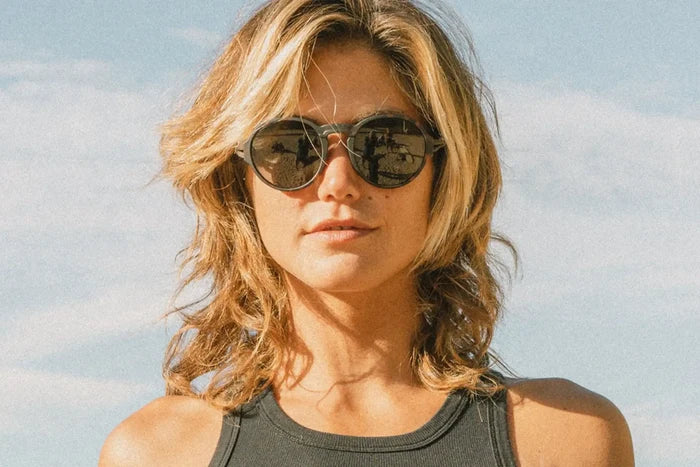Ombraz Viale armless sunglasses, tortoise frame with grey lenses – worn by a woman in a tank top against a bright sky