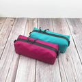 Outdoorline Zipper Pouch Long Ecopak – teal and magenta pouches on wood