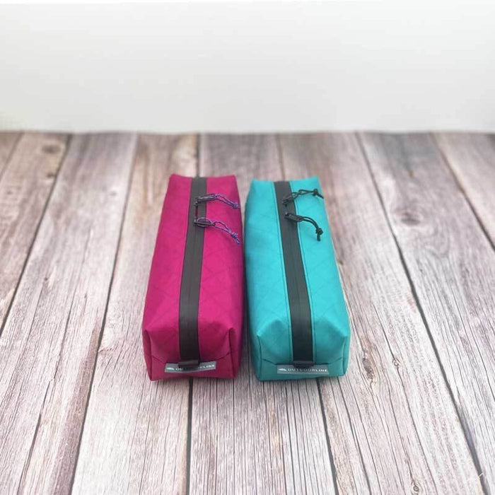Outdoorline Zipper Pouch Long Ecopak – magenta and teal pouches on wood