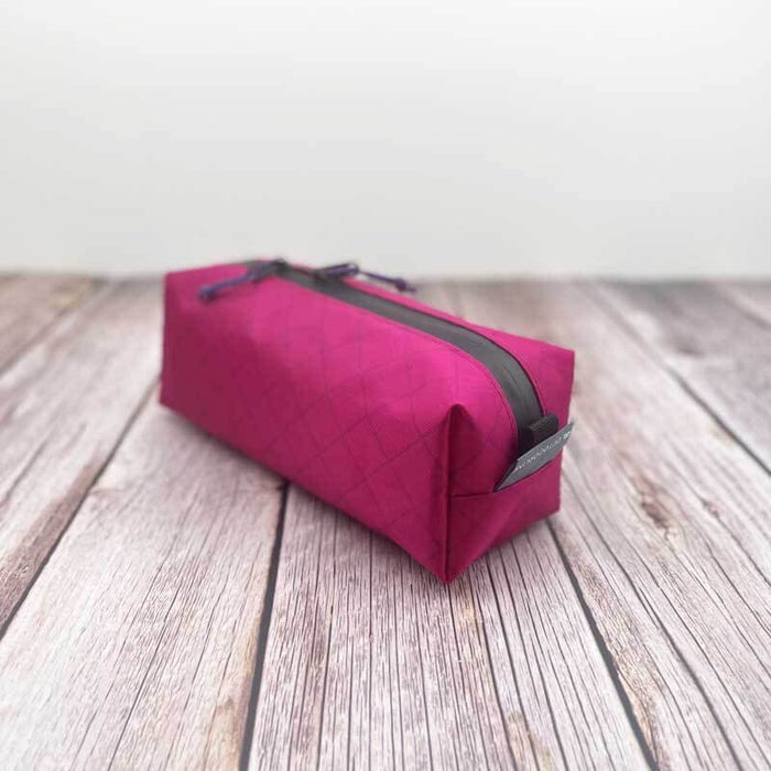 Outdoorline Zipper Pouch Long Ecopak – magenta pouch on wood, side view