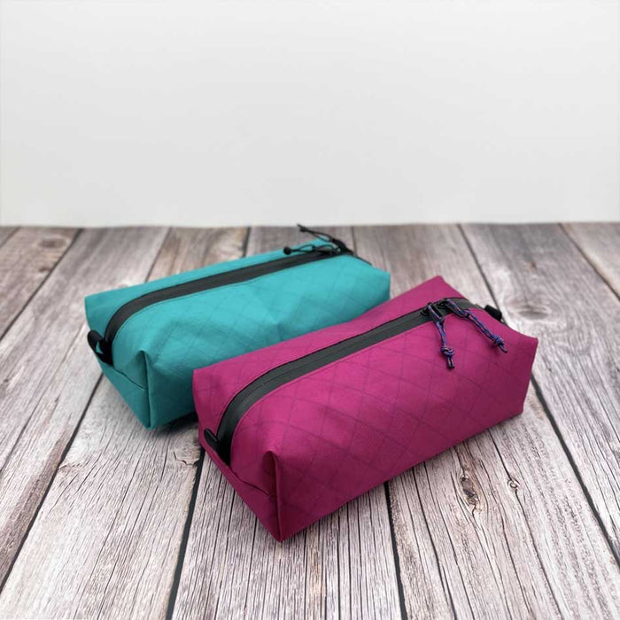 Outdoorline Zipper Pouch Wide Ecopak – teal and magenta pouches on wood
