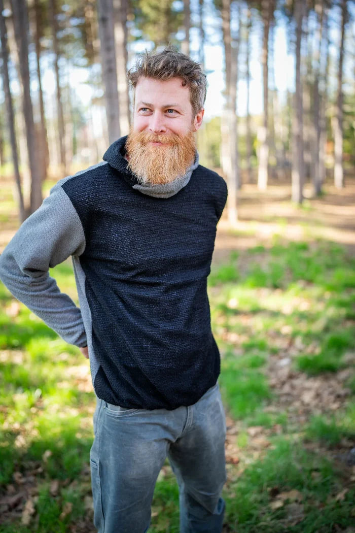 Sambob Alpha 90 Hoodie in Black/Flint – worn by a bearded hiker in a pine forest, hood down