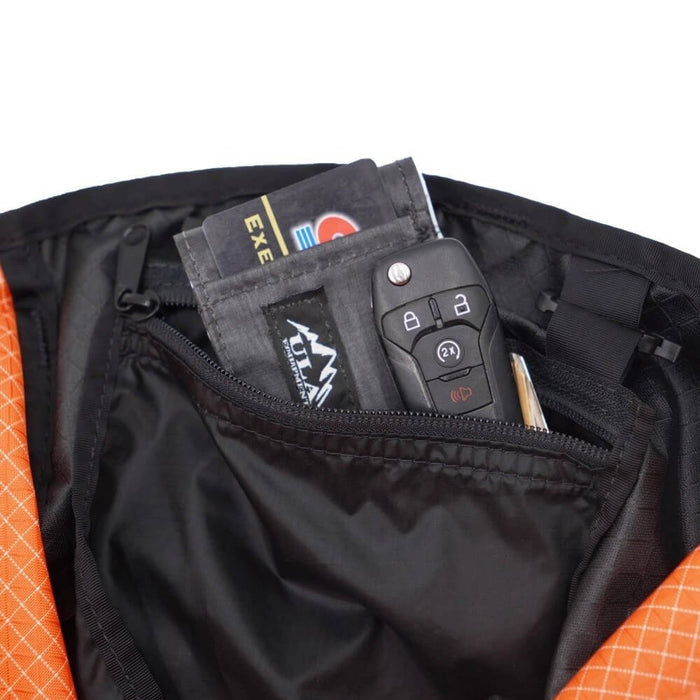 ULA Internal Stash Pocket holding car keys, a wallet and a pen inside an orange pack