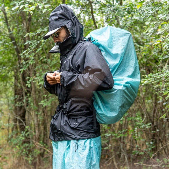 ULA Pack Cover in teal over a pack worn in the rain, hiker in a hooded shell jacket