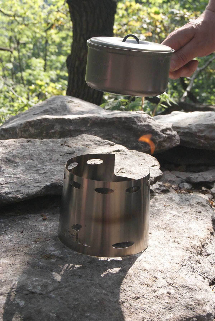 VESUV Titanium Windshield 0,9 L on a rock, hand adding the pot lid